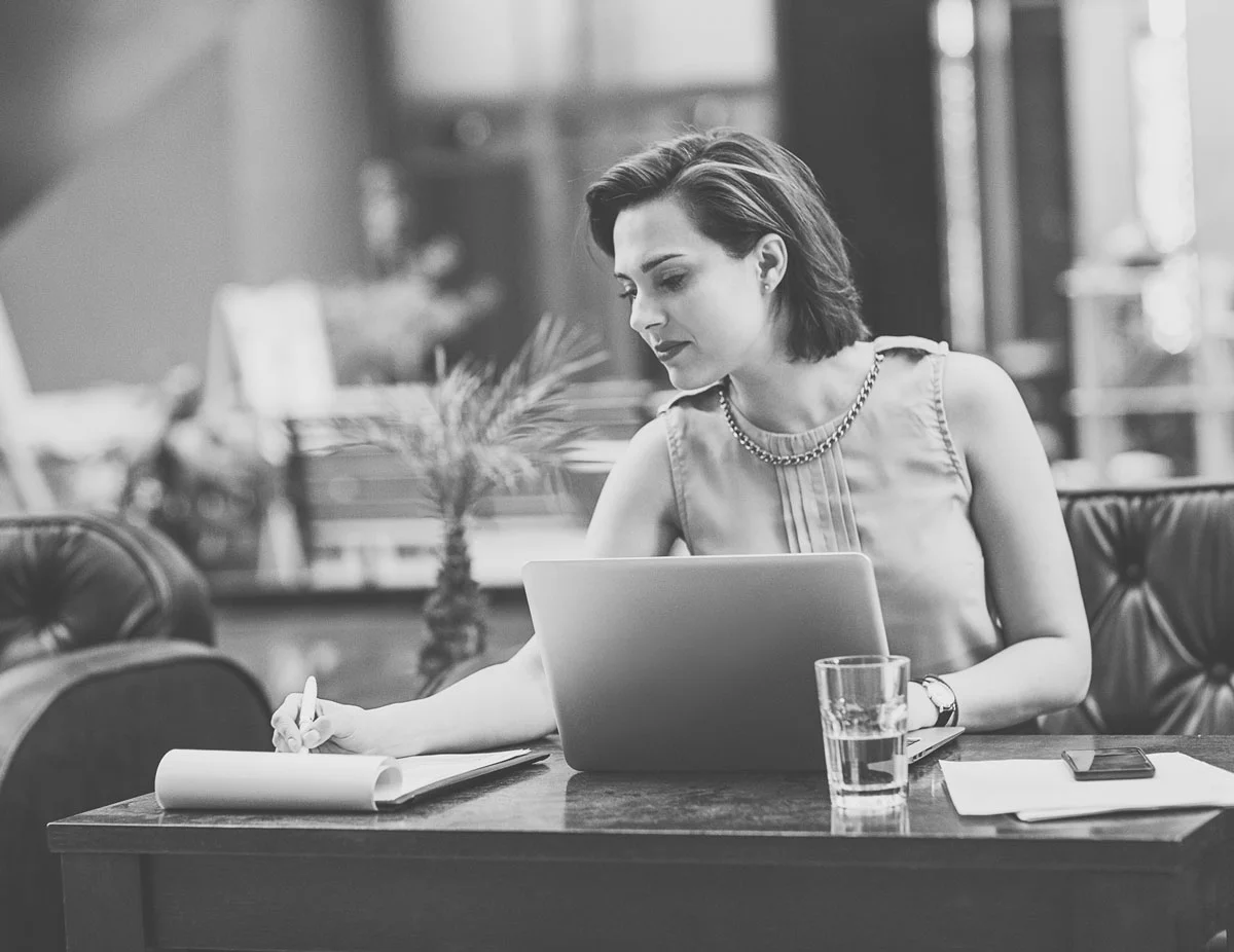 A person taking notes in front of a laptop