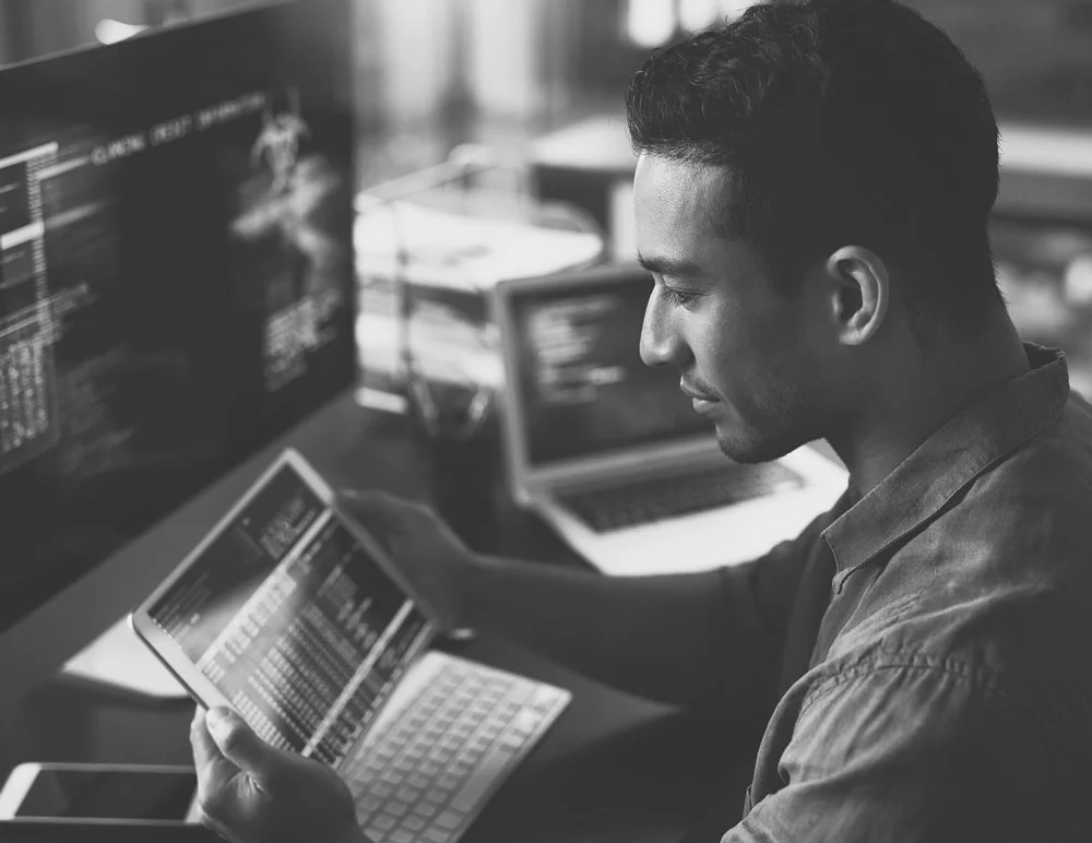 A person taking notes in front of a laptop