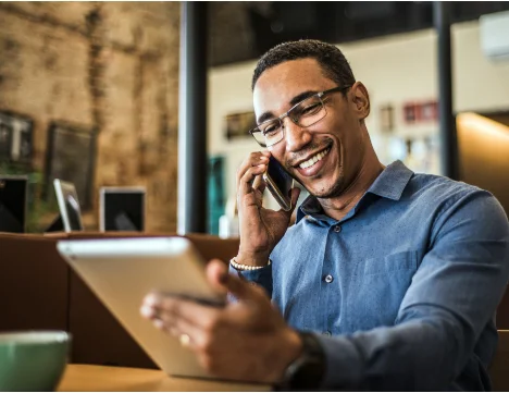 A man on the phone holding a tablet